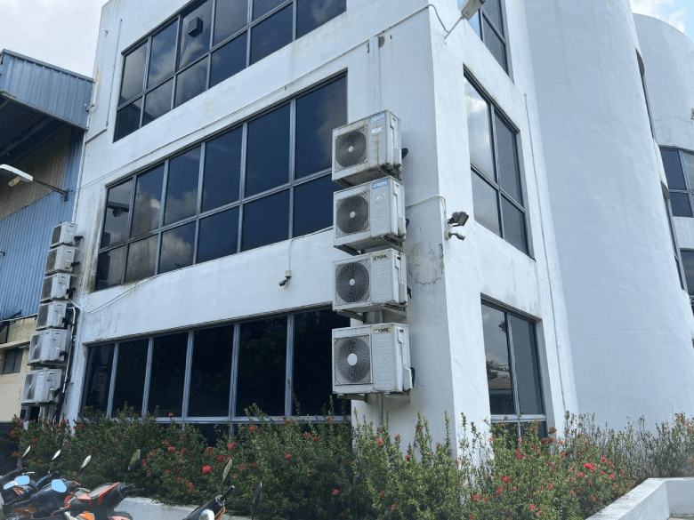 White modern office building with large glass windows and stacked outdoor air conditioning units on the corner wall